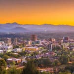Panoramablick auf die Skyline von Asheville, North Carolina, mit den Bergen der Blue Ridge Mountains bei Sonnenuntergang.