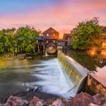 Eine historische Wassermühle (Old Mill) am Wasserfall in Pigeon Forge, Tennessee, bei Sonnenuntergang.
